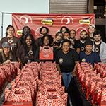 Full Sail volunteers and members of the Agape Roots Foundation pose with dozens of "Thrive Pack" care packages.