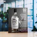 A copy of 'Graphic Design USA' magazine sits atop a white surface against a blurred background. The magazine cover depicts a bottle of gin and a martini glass against a gray background and reads '61st Anniversary American Package Design Awards.