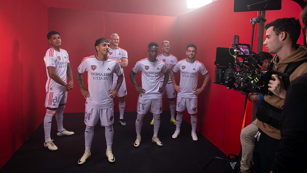 六名身着全套队服的足球运动员在红色背景下拍摄.